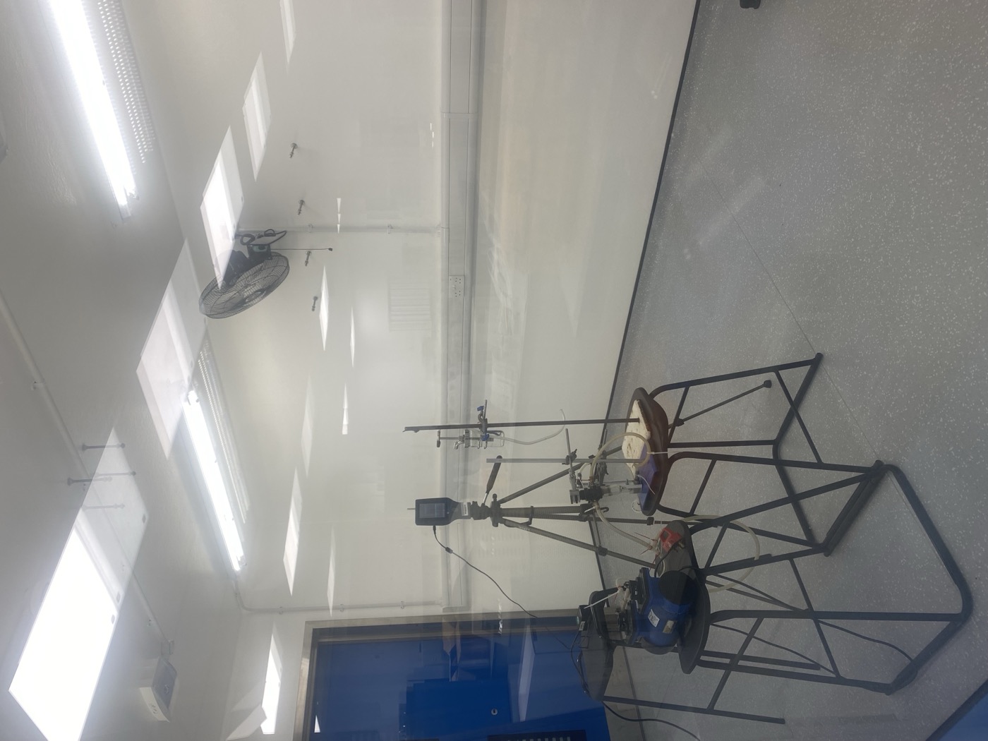 Sampling instruments mounted on tripods and stands inside the brightly lit chamber, with a wall-mounted fan above
