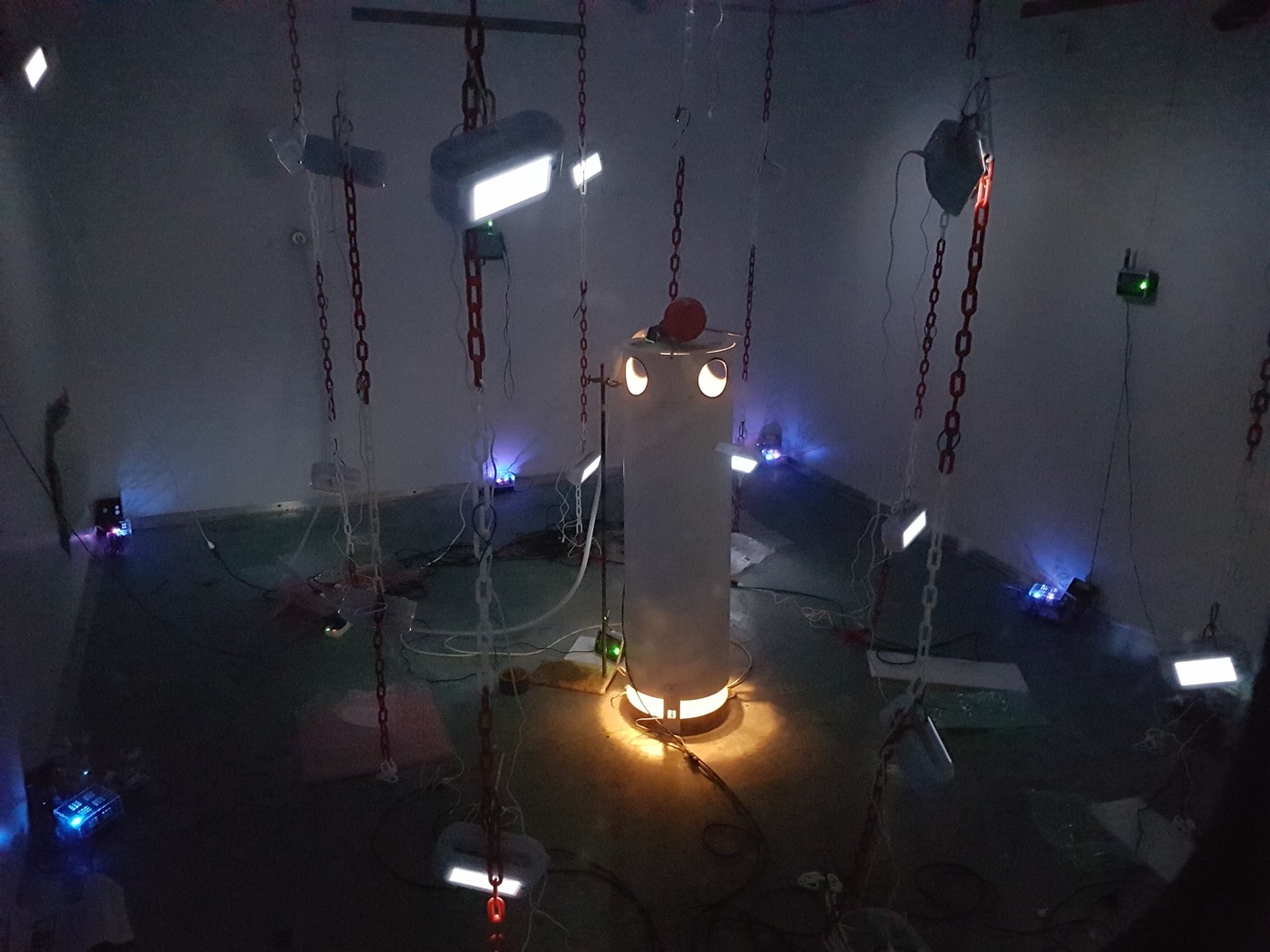 A heated thermal manikin in the darkened aerobiology chamber, surrounded by sensors