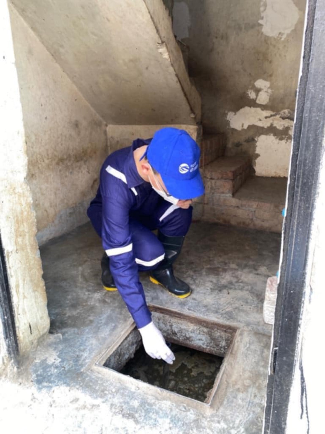 A researcher sampling sludge from a pit latrine