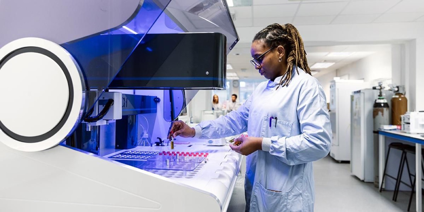 A researcher loading sample vials into the HACH analytical robot in a laboratory